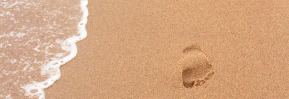 A footprint on a sandy beech represents the carbon footprint of a magazine